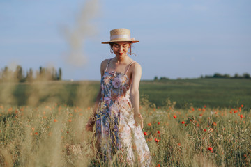 Fototapeta na wymiar Young woman walking on flower field at sunset on background. Horizontal view with copy space