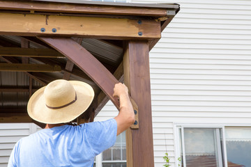 Man in straw sunhat painting a wooden gazebo