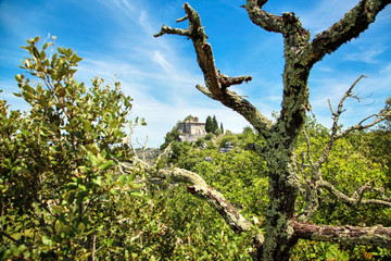 An old stone chapel, a church or a monastery standing on the edge of a rock. White fluffy clouds and blue sky. South France, Europe