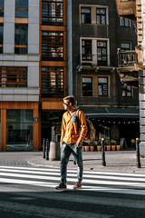 The guy crosses the street through the pedestrian crossing. Stylishly dressed man with a briefcase in a hurry to work and study. The man travels to the cities of .Europe. Poland Warsaw.