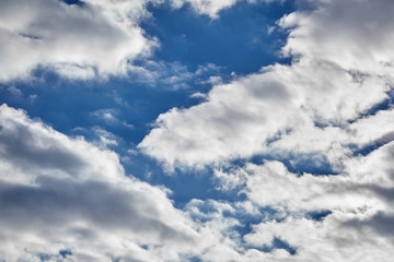 white fluffy soaring clouds on a blue sky background