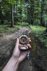 Man with compass in hand in lush summer forest. Travel concept