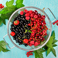 Fresh summer berries in a basket on turquoise background