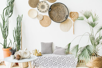 Modern minimal home interior design. Pillows, golden teapot, decorative straw plates, Scandinavian blanket, tropical palm tree, succulent and decorations. - obrazy, fototapety, plakaty