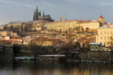 Sunny snowy early morning Prague Lesser Town with gothic Castle above River Vltava, Czech republic