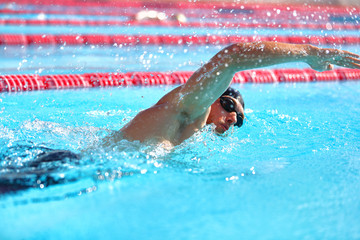 Triathlon fitness athlete man training cardio swimming in outdoor pool at stadium. Swimmer man swmming in blue water . Sport and fitness exercise.
