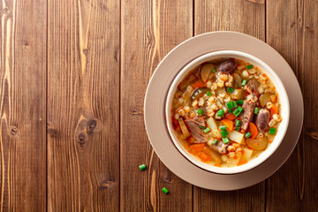 Traditional Russian soup Rassolnik with pickled cucumbers and pearl barley in bowl on wooden table