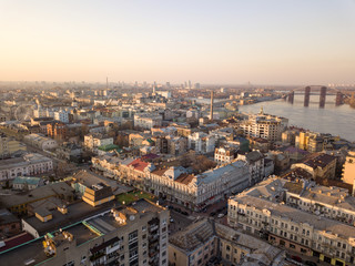 Fototapeta premium The panoramic bird's eye view from drone to the central historical part of the city Kiev - the Podol district, the Dnieper River in Kiev, Ukraine at summer sunset.