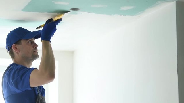 refurbishment. Plasterer spackling a gypsum plasterboard ceiling with putty