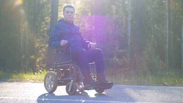 Paraplegic person is sitting in a wheelchair outside and looking into the camera