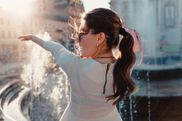 Happy young woman tourist enjoys fountain. Summer travel. Vacation and holidays concept