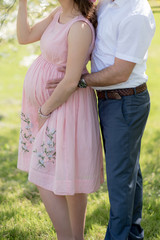 Happy and young pregnant couple hugging in nature - Detail of young pregnant couple - New Family