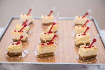 Fancy beautiful mini cakes on wooden plate on even snack table