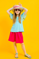 Girl with red hair on a yellow background. A charming girl in bright summer clothes made herself horns.