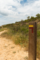 Fingerpost in the Algarve, Portugal. These fingerposts are used to mark walking routes and have recognisable red and yellow markings with different patterns for each sign, in this case turn left.