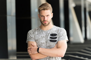 Man bristle serious face muscular shoulders, urban background, defocused. Man beard unshaven guy looks handsome and cool. Metrosexual concept. Guy bearded and attractive cares about appearance