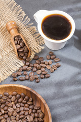 Coffee cup and coffee beans on a wooden table and sack background,Vintage color tone
