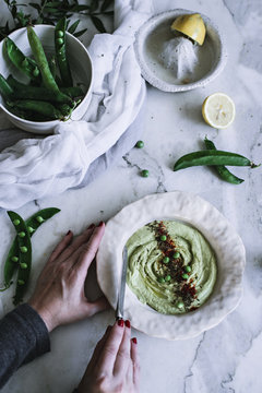 Overhead view of woman's hand preparing mushy peas in bowl
