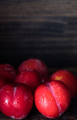 Red plum over dark wooden background