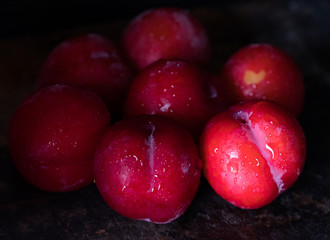 Red plum over dark wooden background