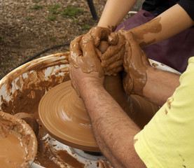 Potter and child hands molding mud