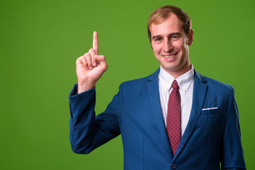 Young businessman against green background
