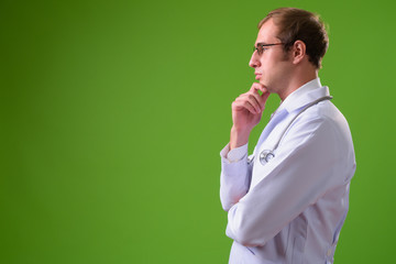 Young man doctor against green background