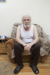 Old sick lonely man in the armchair at home