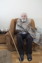 Old sick lonely man in the armchair at home