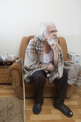 Old sick lonely man in the armchair at home