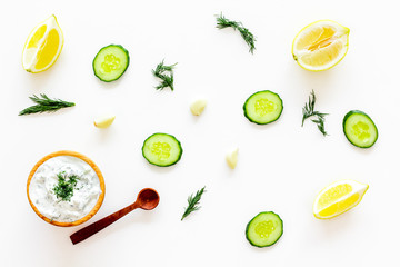 Greek yogurt dip with greenery, cucumber, oranges, garlic on white background top view pattern