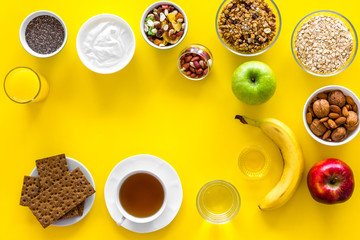 Ideas of healthy hearty breakfast for sportsmen. Fruits, oatmeal, yogurt, nuts, crispbreads, chia on yellow background top view copy space