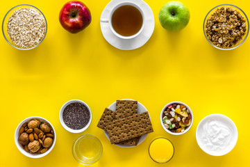 Ideas of healthy hearty breakfast for sportsmen. Fruits, oatmeal, yogurt, nuts, crispbreads, chia on yellow background top view copy space