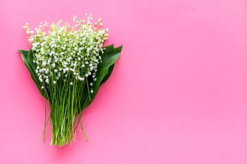 May flowers. Bouqet of lily of the valley flowers on pastel pink background top view copy space