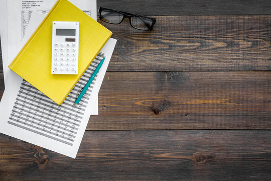 Math textbook or tutorial near sheet with numbers, countes and calculator ondark wooden background top view copy space