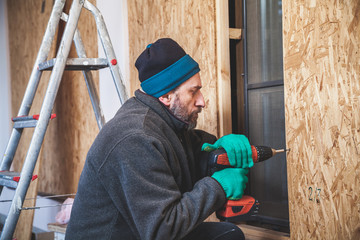 man with beard twists screw with tool