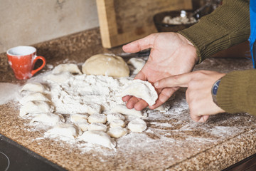raw dumpling is on man hand in kitchen