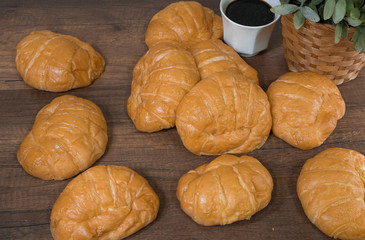 Freshly baked homemade croissants and black coffee on wooden cutting board, top view