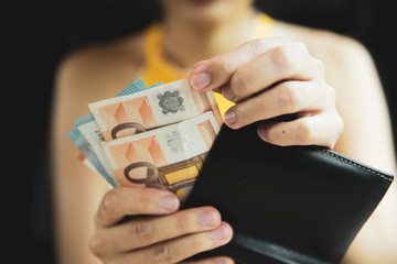 A female hand piking up or counting money in the wallet.
