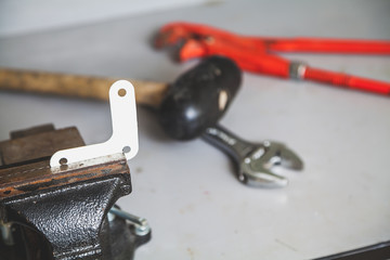 White corner clamped in vise. Behind lie mallet and wrenches