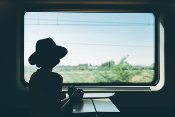 Silhouette of hipster asian woman holding camera, traveling on the train. woman traveling alone by...