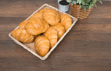 Freshly baked homemade croissants and black coffee on wooden cutting board, top view