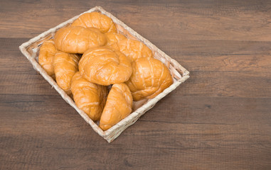 Freshly baked homemade croissants and black coffee on wooden cutting board, top view