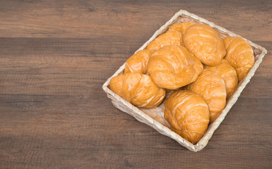 Freshly baked homemade croissants and black coffee on wooden cutting board, top view