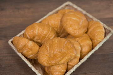 Freshly baked homemade croissants and black coffee on wooden cutting board, top view
