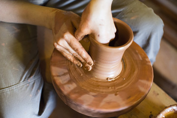 Rotating potter's wheel and clay ware on it taken from above. Hands in clay. Pottery male ceramist creates a hand made clay product. Process of rotation of potter's wheel, hands of ceramist