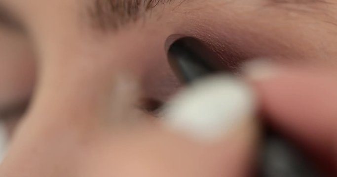 Extra close up macro of female eye with ideal make up. Professional artist applying blending eye shadows on eyelid with special tool brush pencil. Process beautification in beauty salon 4k cosmetology