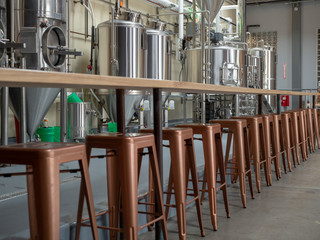 Counter top and cooper stools sitting in front of brewery tanks and equipment