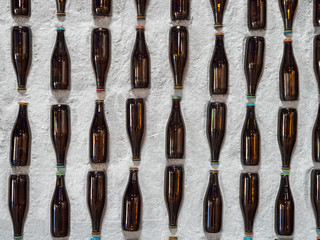 A display of mounted empty beer bottles embedded into a stone wall
