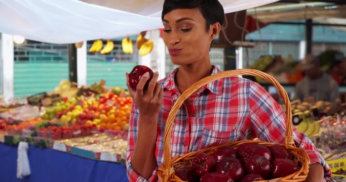 Cheerful smiling young black woman bites into juicy apple, Healthy attractive female at the farmer's market eating fresh organic fruit, 4k